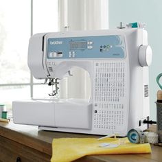 a white sewing machine sitting on top of a wooden table next to a yellow towel