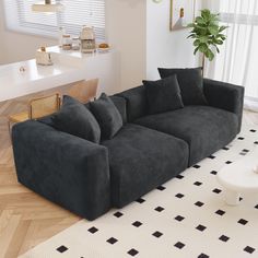 a large black couch sitting on top of a white floor next to a wooden table