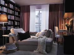 a man laying on top of a couch in a living room next to a book shelf