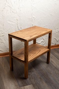 a wooden table sitting on top of a hard wood floor next to a white wall