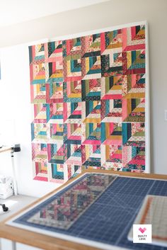 a quilter's work table with a large piece of fabric on the wall