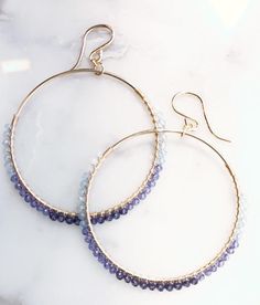 1 3/4" semi precious gemstone hoops, hand wire wrapped in dallas texas. 14kt Gold Filled components. Very light, see Neutral version as well. Bluebird: blue lace agate, blue topaz, iolite, teal topaz Neutral: pyrite, mystic labradorite, mystic moonstone Blue Beaded Amethyst Jewelry, Handmade Blue Amethyst Jewelry, Blue 14k Gold Filled Jewelry With Ear Wire, Bohemian Blue 14k Gold Filled Jewelry, Blue Beaded Jewelry In 14k Gold Filled, Blue Bohemian 14k Gold Filled Jewelry, Blue 14k Gold Filled Hoop Jewelry, Hand-wrapped Blue Round Jewelry, Blue 14k Gold Filled Nickel-free Jewelry