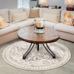 a living room filled with furniture and a round table on top of a white rug