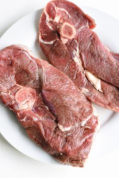 two pieces of raw meat on a white plate