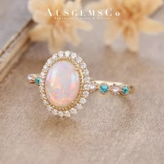 an opalite and diamond ring sits on top of a book with flowers in the background