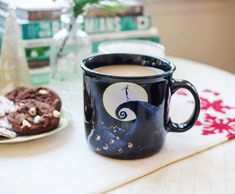 a cup of coffee sitting on top of a table next to a plate of cookies