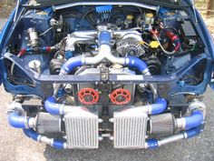 the engine compartment of a blue car with red hoses on it's sides