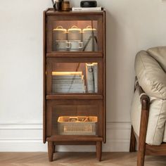 a wooden shelf with some books and other items on it next to a chair in a living room