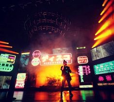 a man standing on top of a stage in front of neon signs