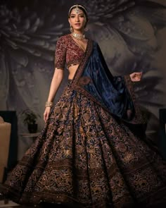 a woman in a blue and gold lehenga is posing for the camera with her hands on her hips