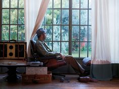 a man sitting in a chair with his feet up on the floor next to a window