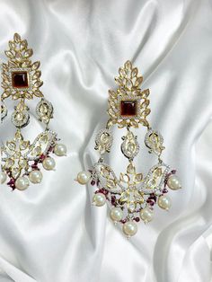 Introducing our exquisite Gold Indian Earrings adorned with radiant rubies and mesmerizing uncut polki, a true testament to timeless elegance and traditional craftsmanship. These captivating earrings are designed to enhance your beauty and add a touch of regal charm to any ensemble. 🌟 Features: 🔸 Material: High-quality gold-plated metal 🔸 Gemstones: Rich red rubies and sparkling uncut polki 🔸 Length: Gracefully long, these earrings dangle elegantly 🔸 Colors: Available in three enchanting sh Elegant Ruby Chandelier Earrings For Festive Occasions, Elegant Red Chandbali Danglers, Bollywood Style Ruby Chandbali Jhumkas, Elegant Ruby Danglers For Celebration, Elegant Ruby Chandbali Danglers, Heavy Ruby Jhumkas For Festive Occasions, Festive Heavy Ruby Jhumkas, Bollywood Style Ruby Jhumkas With Intricate Design, Bollywood Style Bridal Earrings With Gold And Ruby