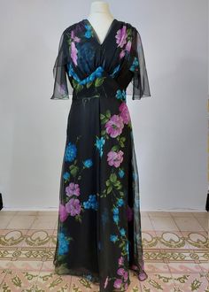 A super example of a perfect summer wedding maxi dress. For those of you who don't like to wear colour but can't wear black to a wedding, this is ideal because the floral design pops! the dress has a ruched v neck and an angel sleeve capelet perfect for keeping upper arms hidden. it has a round back and fastens at the back with a zipper. MEASUREMENTS  * All measurements taken flat then doubled - please ensure fit before purchasing BEST FIT: UK 12  /US  8 / EU  40 APPROX!  - please go by measurements below: Bust: 37 ins/ 94cm  Waist : 29 ins/ 74cm  Hips: free Length (shoulder to hem):57ins/ 145cm Condition: Excellent. She has been professionally cleaned and is ready to wear. There are no noticeable holes or stains on the dress please contact me with any questions or if you want additional p Flowy Full Length Evening Dresses, Formal Fitted Chiffon Dress With Short Sleeves, Formal Fitted Short Sleeve Chiffon Dress, Black Maxi Length Evening Dress For Summer, Black Maxi Length Summer Evening Dress, Black Maxi Evening Dress For Summer, Summer Empire Waist Maxi Dress For Evening, Spring Party Empire Waist Gown, Fitted Short Sleeve Chiffon Evening Dress