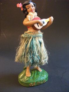 a figurine of a hula girl holding a guitar and wearing grass skirt