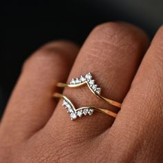 a woman's hand with two gold rings on it and one diamond ring in the middle