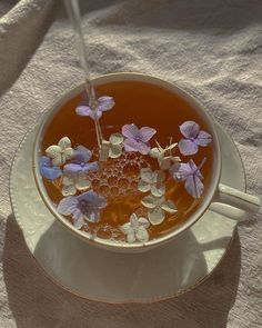 a cup filled with liquid and flowers on top of a saucer