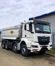 a white dump truck parked in front of a building