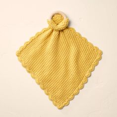 a yellow crocheted baby blanket with a wooden ring on it's end