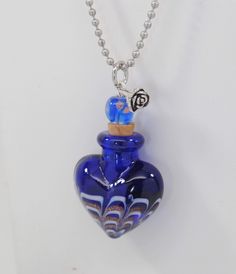 a blue glass heart shaped bottle with a silver ball chain on a white background,