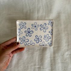 a hand holding a blue and white flowered ceramic dish