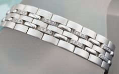 GENTS SIMULATED DIAMONDS BRACELET IN 14 KARAT WHITE GOLD DESIGN FOR JEWELRY SHOW. SKU-ART2 SETTING INFORMATION METAL ---------------14 KARAT WHITE GOLD SETTING -----------------PRONG SET FINISH------------HIGH POLISH AND SATIN FINISH WIDTH------------------------14 MM WEIGHT-47.5 GM SIMULATED DIAMONDS INFORMATION QUANTITY------------------------72 SHAPE-----------------------ROUND TOTAL WEIGHT----------------.75 CARAT CUSTOM ORDERS: Please feel free to contact us if you could not find the piece Anniversary Diamond Bracelet With Solid Link Construction, Silver Diamond Bracelet With Solid Link Construction, Luxury Diamond Bracelet With Solid Link For Anniversary, Luxury Diamond Bracelet For Anniversary, Luxury Silver Diamond Bracelet With Solid Link, Luxury Platinum Diamond Bracelet With Polished Finish, Modern Silver Diamond Bracelet With Diamond Cut, Silver Diamond Bracelet With Polished Finish, Modern Platinum Bracelets In Diamond White