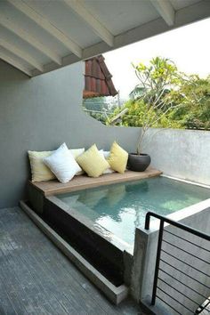 an indoor swimming pool in the middle of a patio with seating and pillows on it