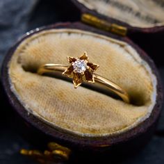 an engagement ring with a diamond in it sitting on top of a velvet box,