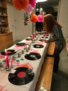 a woman standing at a long table with record records on it and candles in front of her