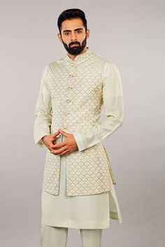 Mint kurta with band collar and full sleeves. Paired with self embroidered jaal bundi and straight pant. 
Component: 3
Embroidered
Neckline: Band Collar
Sleeve Length: Kurta: Full; Bundi; Sleeveless
Fabric: Silk
Color: White
Embroidered bundi
Front button placket
Straight fit pant - Aza Fashions Collar Kurta, Straight Fit Pants, Nehru Jacket, Silk Kurta, Nehru Jackets, Embroidered Neckline, Band Collar, Fabric Silk, Full Sleeves