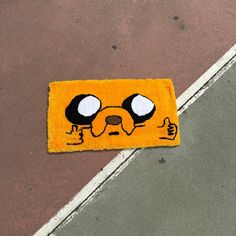 a rug with a face drawn on it sitting in the middle of a parking lot