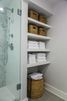 a bathroom with white towels and baskets on the shelves