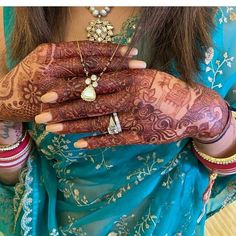 a woman with henna on her hands and jewelry around her neck, holding onto the palm of her hand