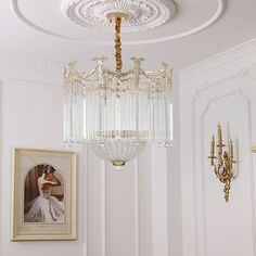 a chandelier hanging from the ceiling in a room with white walls and gold trim