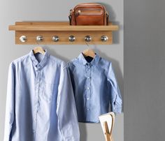 a pair of shirts hanging on a coat rack next to a handbag and purse