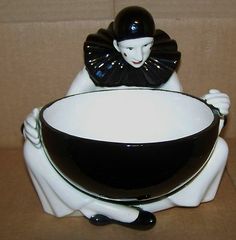 a black and white bowl sitting on top of a table next to a figurine