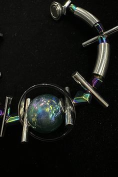 Experience the perfect fusion of futuristic vibes and avant-garde flair with our Planet Beaded Bracelet. At its center, the bracelet features a metal sphere surrounded by circular rings, resembling a celestial body. Interspersed along the bracelet are several elongated cylindrical beads, reminiscent of thorns, adding a touch of edginess to the design. In addition to the metal elements, the bracelet also features beads that reflect neon lights, creating a mesmerizing and futuristic effect. Crafte Modern Metal Beaded Bangle Bracelets, Modern Silver Beaded Bracelets, Modern Silver Bracelets With Silver Beads, Modern Silver Bracelet With Silver Beads, Modern Silver Beaded Bracelets For Jewelry Making, Silver Fusion Bracelets For Party, Unique Silver Metal Beaded Bracelets, Modern Silver Bracelets With Round Beads, Modern Silver Bracelet With Round Beads