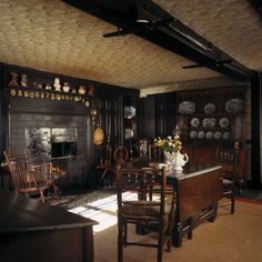 an old fashioned dining room with wood paneling and antique furniture, including a fireplace