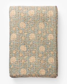 a blue and beige blanket with flowers on it