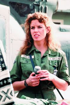 a woman in uniform standing next to an air force plane and talking on the phone