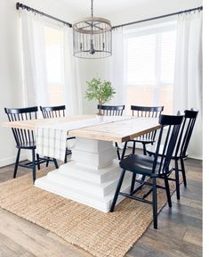 a dining room table with black chairs and a chandelier hanging from the ceiling