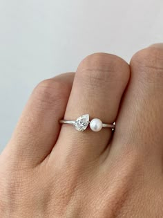 a woman's hand with a pearl and diamond ring