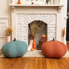 three different colored pillows sitting on the floor in front of a fire place and fireplace