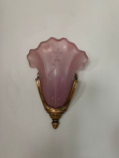 a pink glass vase sitting on top of a wall