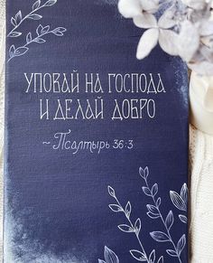 a blue book with white writing on it next to some flowers and a lace doily