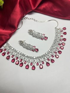 Gorgeous fine quality Wine Red dark pinkish zircon and  diamonds studded necklace with white gold rhodium plating and matching Earrings Item contains: Necklace and earrings AAA quality cubic zirconia used. Highest quality and craftsmanship Necklace Fitting is adjustable Earrings Closure: Pushback Necklace Closure: chain with adjustable length Hook Details-  -Handmade item -Delivery from a small business in India -Materials: white rhodium, stones, cz, zircon, American diamond -Jewellery type: Ear Party Ruby Necklaces With Sparkling Stones, Ruby Necklaces With Sparkling Stones For Party, Ruby Jewelry With Diamond Accents For Party, Party Ruby Necklace With Sparkling Stones, Red Ruby Drop Jewelry, Ruby Necklace For Party, Fine Jewelry, Dazzling Ruby Necklace For Party, Silver American Diamond Necklaces For Parties, Silver American Diamond Party Necklace