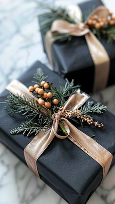 two presents wrapped in black paper and tied with gold ribbon are sitting on a marble surface