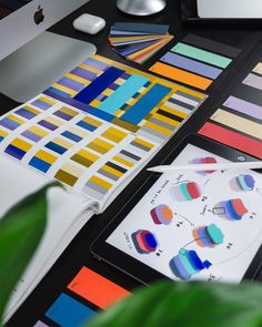 an apple computer sitting on top of a desk covered in color swatches and papers