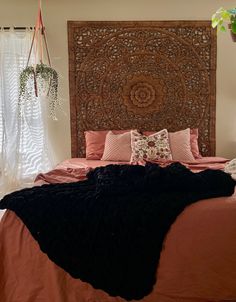 a bed with an intricate wooden headboard and black blanket on it's side