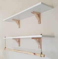 two white shelves with wooden brackets hanging from them