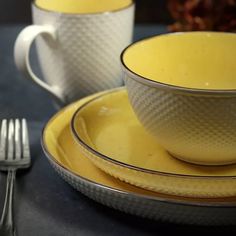 two yellow dishes with silver rims are sitting next to each other on a table